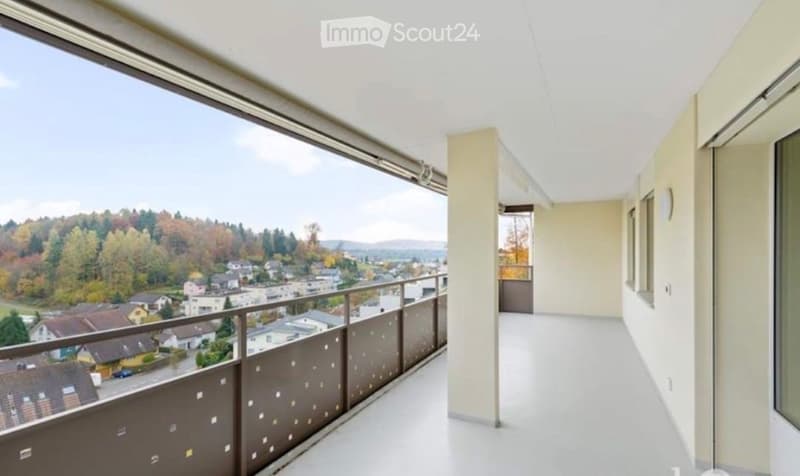 Spacious balcony with white flooring, modern railing, and expansive view of a suburban neighborhood with trees and houses.