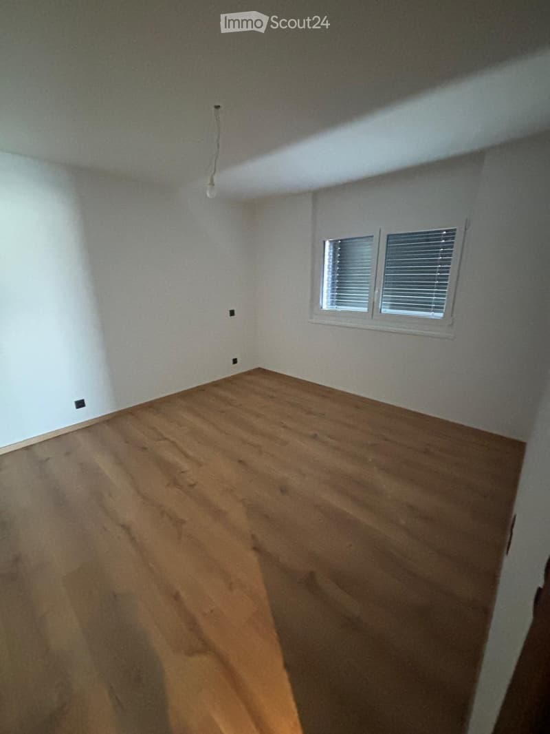 Empty room with wooden flooring, white walls, and two windows with blinds.