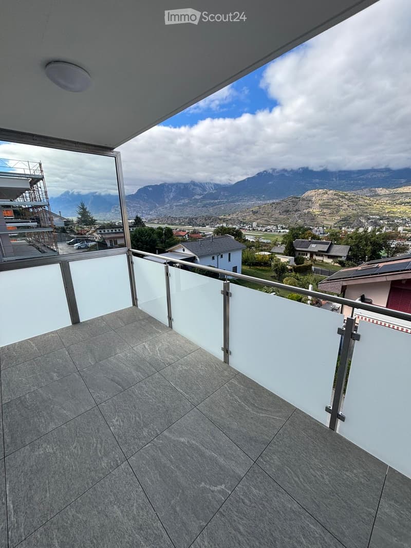 Balcony with modern glass railing, tiled floor, and scenic mountain view.