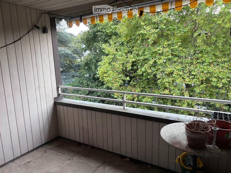 Balcony with wooden decking, white railing, and a small table with potted plants.