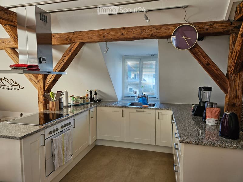 Modern kitchen with white cabinets, granite countertops, stainless steel appliances, and wooden beams on the ceiling.