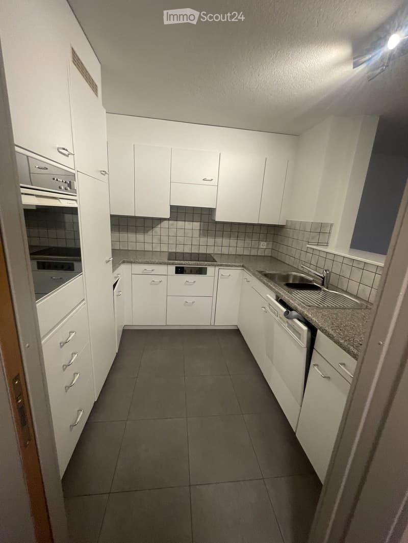 Modern kitchen with white cabinets, granite countertops, and stainless steel appliances including a sink, oven, and dishwasher.
