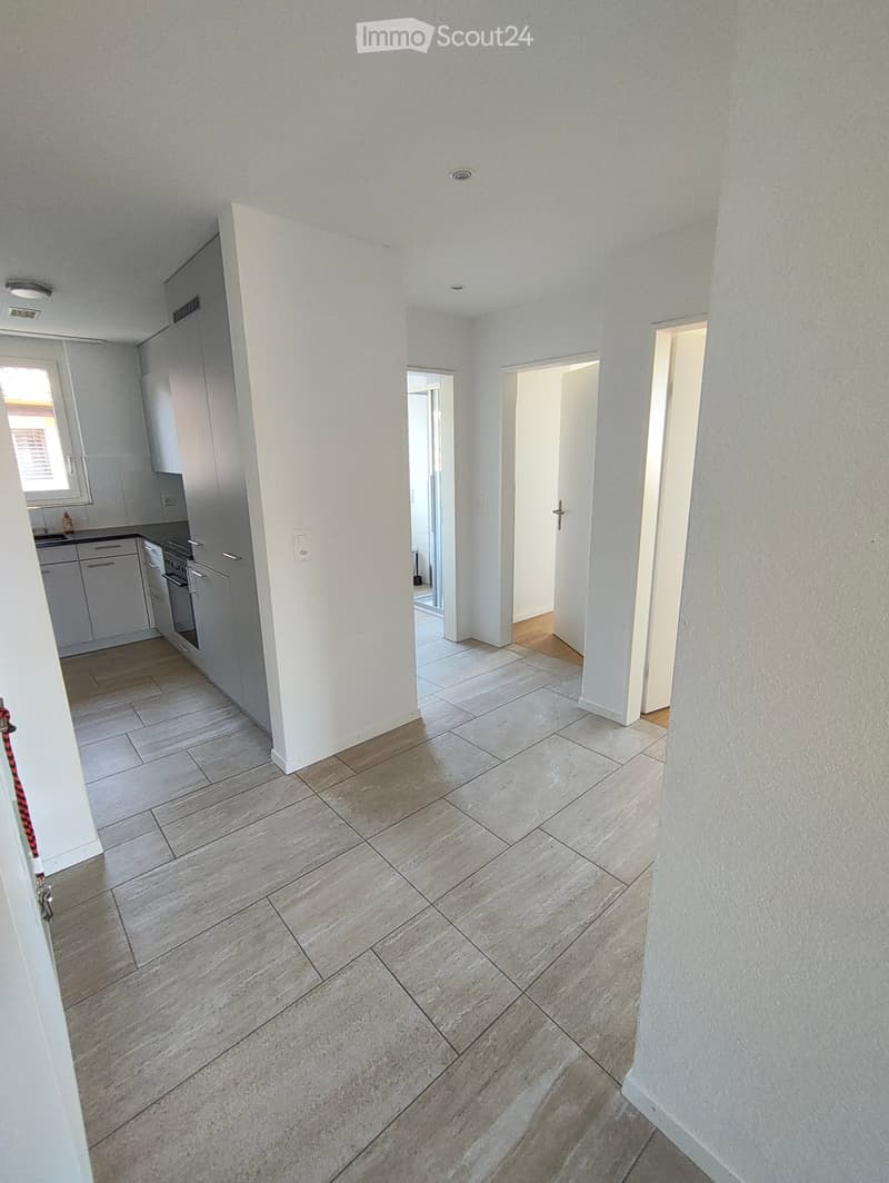 Empty hallway with tiled floor, white walls, and several open doors leading to other rooms.