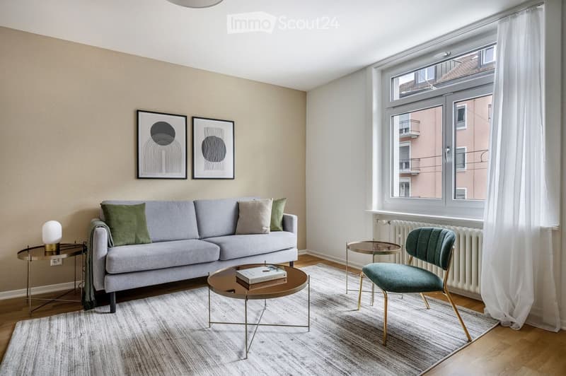 Modern living room with a grey sofa, green cushions, a coffee table, a side table, a chair, and artwork on the wall.