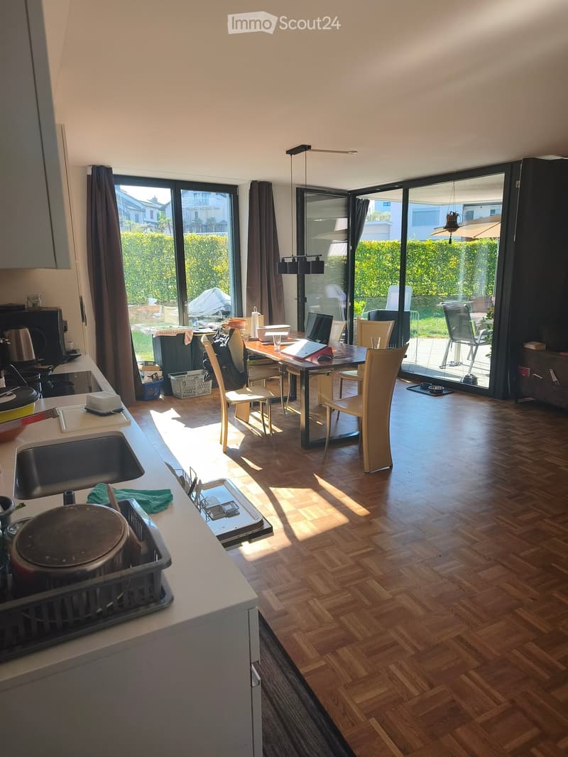 Bright, open-plan kitchen and dining area with wooden flooring, large windows, and modern appliances.