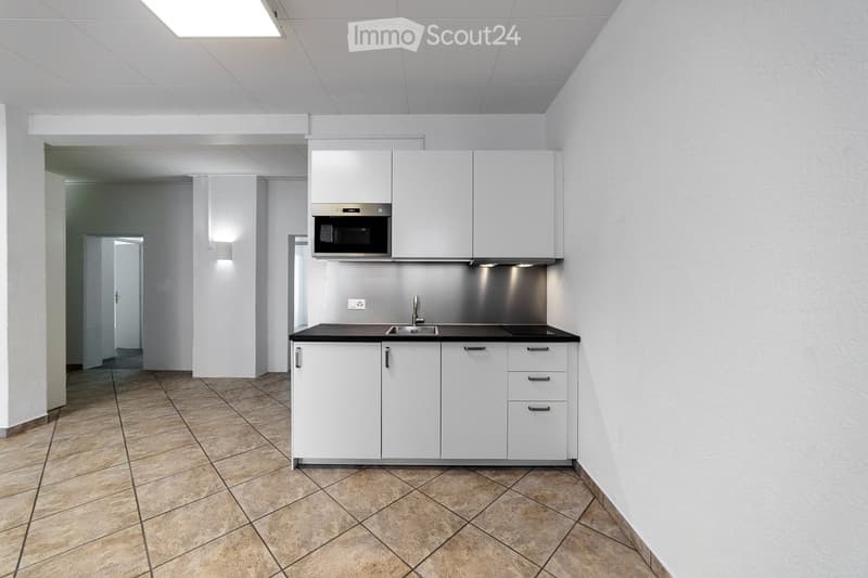 Modern kitchen with white cabinets, a microwave, a sink, and a faucet, featuring tiled flooring and white walls.