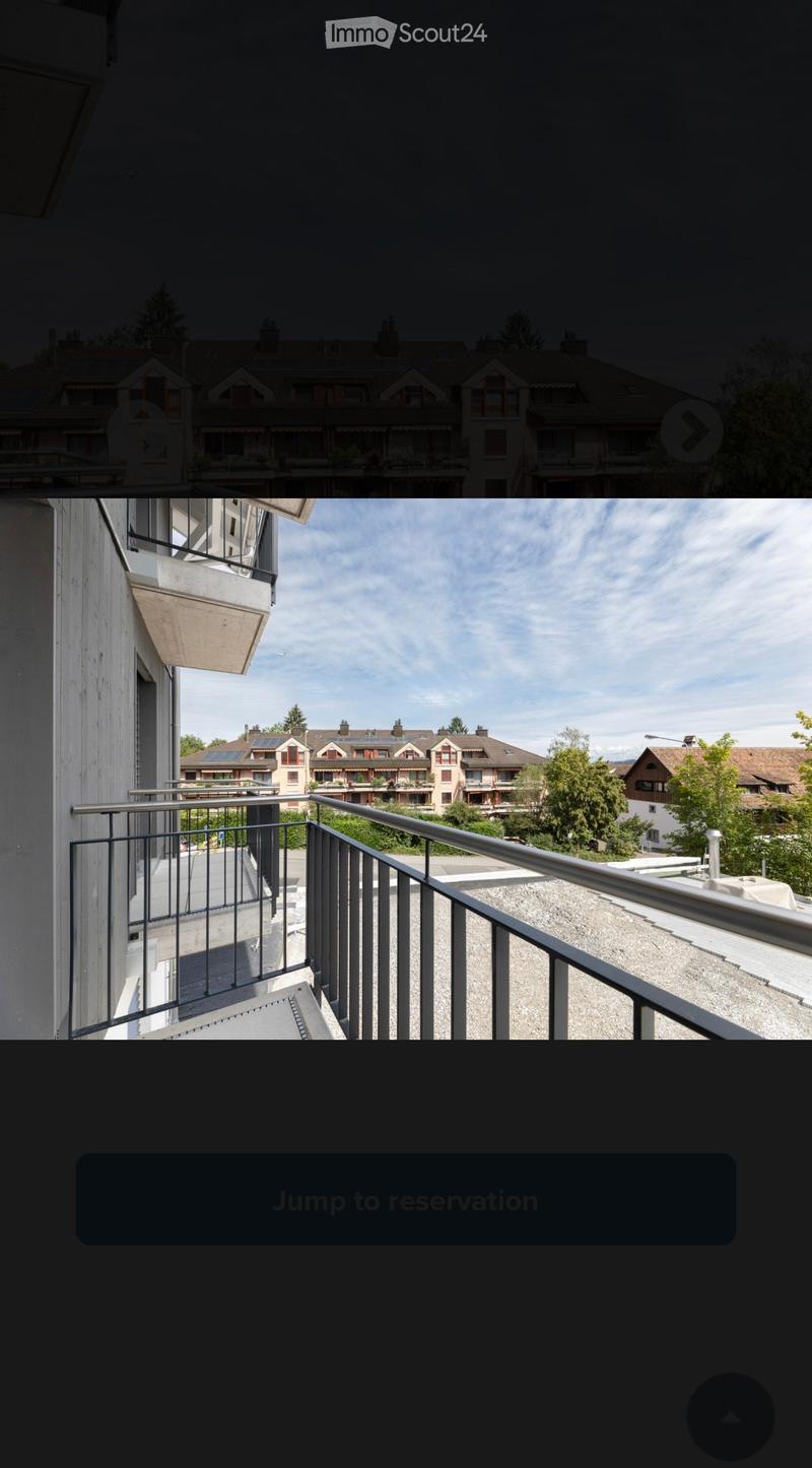 Balcony with metal railing overlooking a residential area with houses, trees, and solar panels on rooftops.