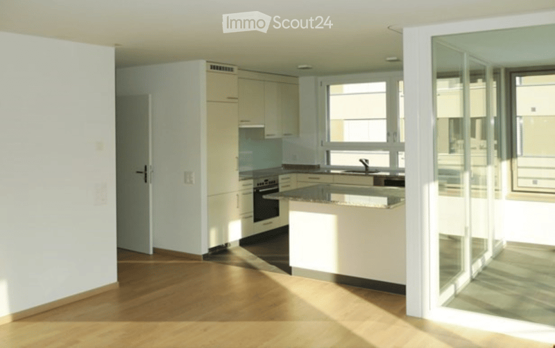 Modern kitchen with white cabinets, a central island, and a dark countertop. Features an oven, sink, and faucet, with large windows allowing natural light to fill the space.