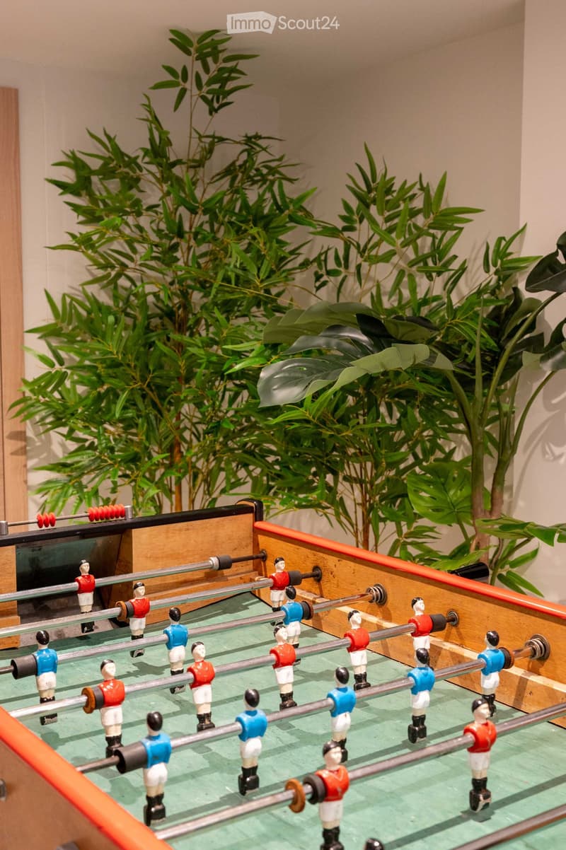 A small room with a foosball table and several potted plants in the background.