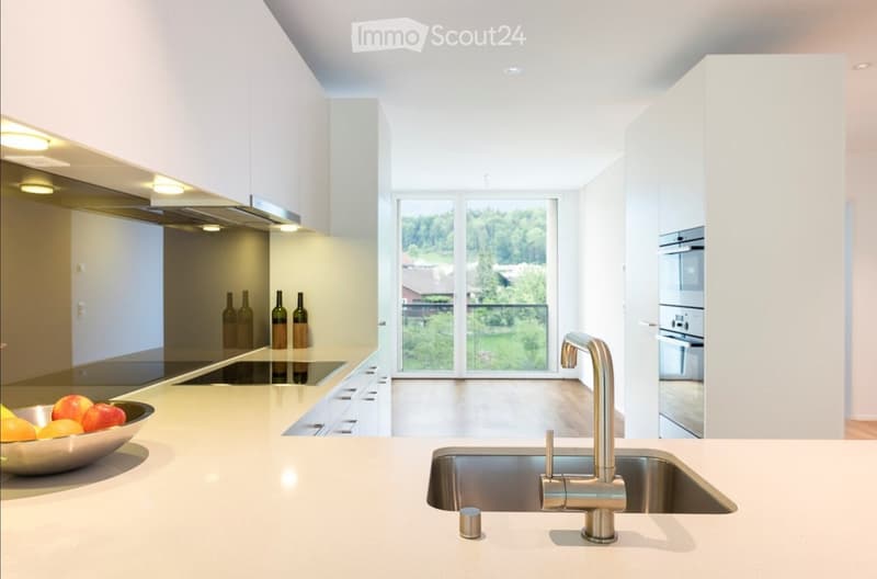 Modern kitchen with white cabinets, stainless steel appliances, a large island, and a view of the outdoors.