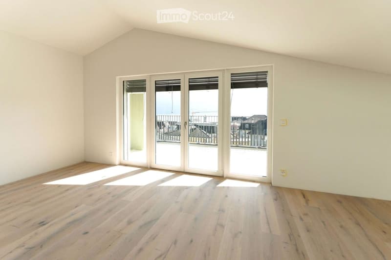 Empty room with wooden flooring and large sliding glass doors leading to a balcony or terrace area.