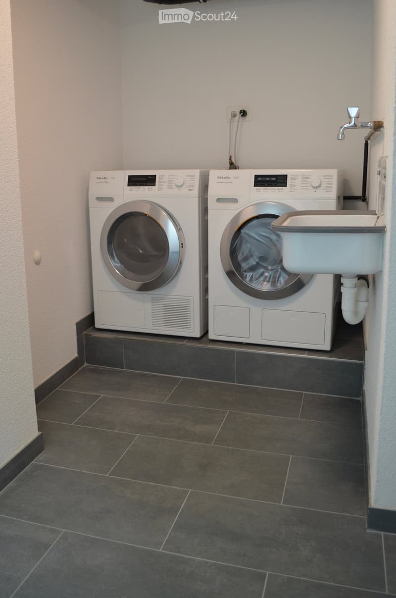 Clean, modern bathroom with a washing machine, dishwasher, and a small sink.
