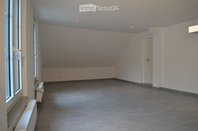Empty room with grey tiled floor, white walls, and large windows. No furniture or equipment visible.