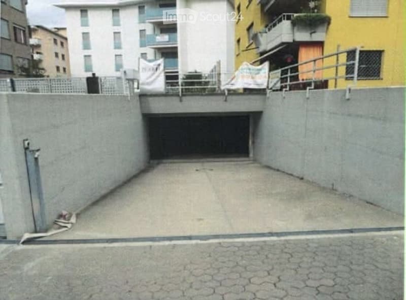 Underground garage with concrete walls and a single entrance ramp leading to the street.