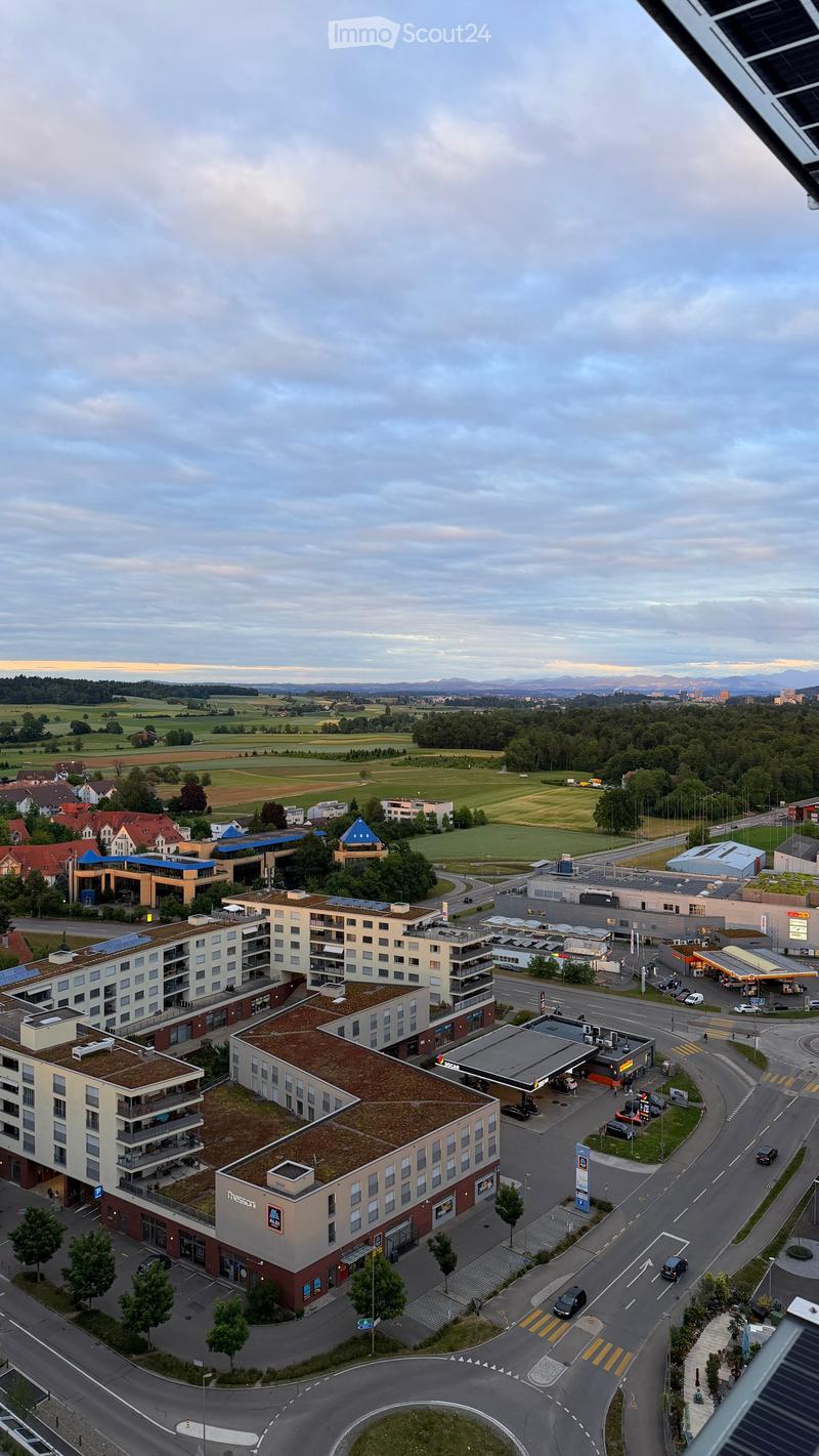 Aerial view of a modern residential and commercial complex with multiple buildings, parking areas, and surrounding greenery.