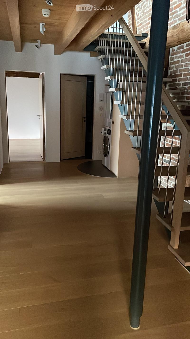 Spacious hallway with wooden flooring, modern staircase with metal railing, and a washing machine in the background.