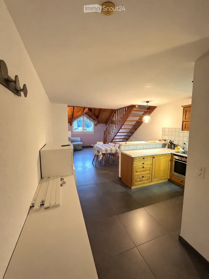 Open-plan kitchen and dining area with modern cabinets, a central island, and a staircase leading to an upper level.