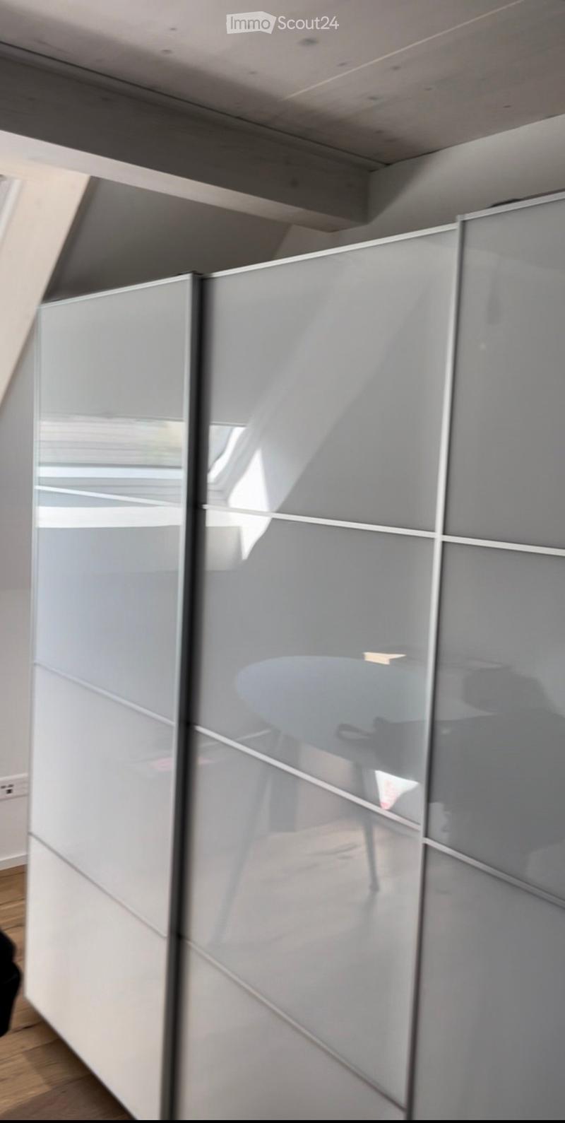 Modern hallway with sleek, grey glass partitions and wooden flooring, featuring a contemporary design with clean lines and ample natural light.