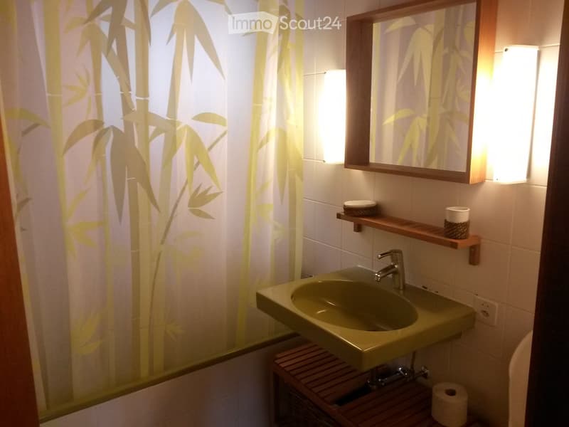 Bathroom with a sink, mirror, wooden shelf, and bamboo-patterned shower curtain.