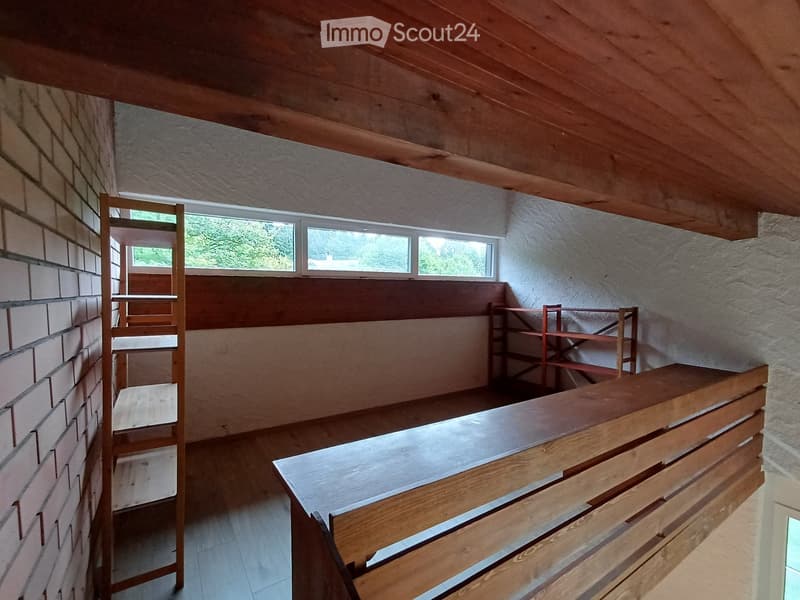 Empty room with wooden ceiling, brick wall, and wooden shelves. No furniture or equipment present.