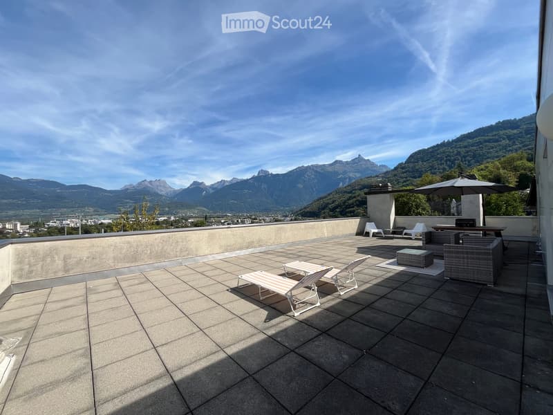 Roof terrace with tiled floor, lounge chairs, small table, umbrella, and scenic mountain view.