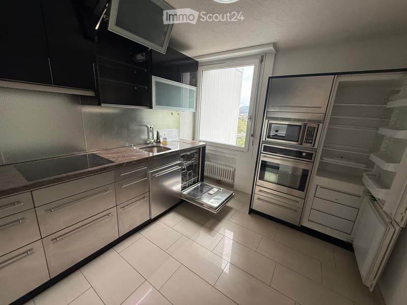 Modern kitchen with stainless steel appliances, granite countertop, and large window letting in natural light.