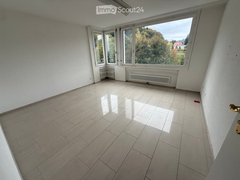 Empty room with tiled floor, large windows, radiators, and white walls.