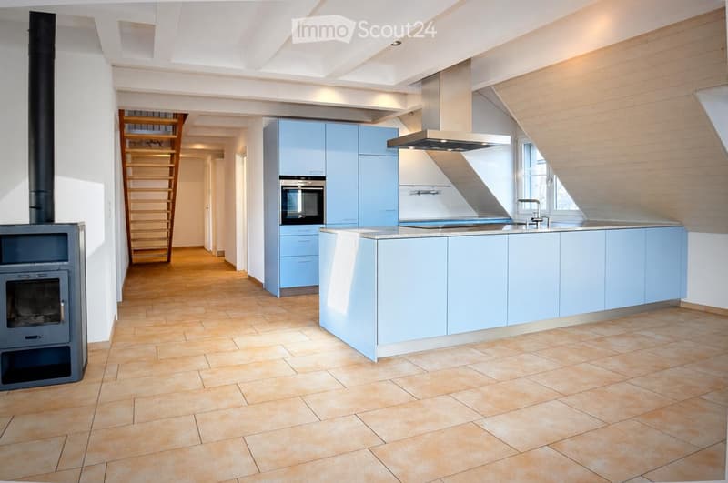 Modern kitchen with light blue cabinets, a central island, a built-in oven, a sink with a faucet, a range hood, and a wooden ladder leading to an upper level.