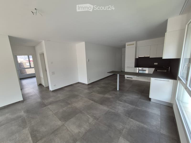 Empty kitchen with white cabinets, dark countertops, and tiled floor. No appliances or furniture present.