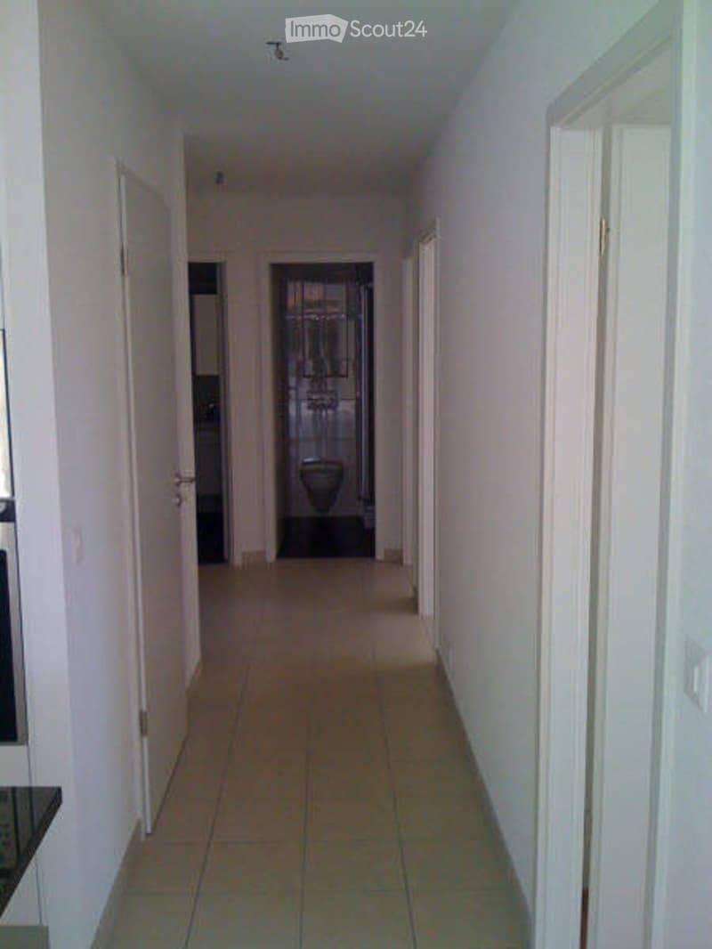 Empty hallway with tiled floor, white walls, and several doors leading to rooms.
