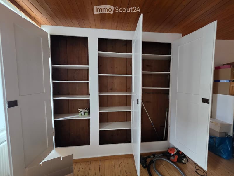 Empty room with wooden floor and white built-in shelving unit. No furniture or equipment visible.