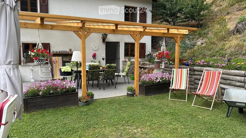 A well-maintained garden with a wooden pergola, outdoor dining area, colorful flowers, and striped lounge chairs.