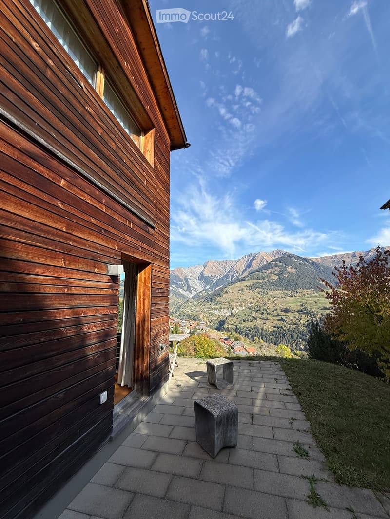 Balcony with stone stools, overlooking a scenic mountain view and valley.