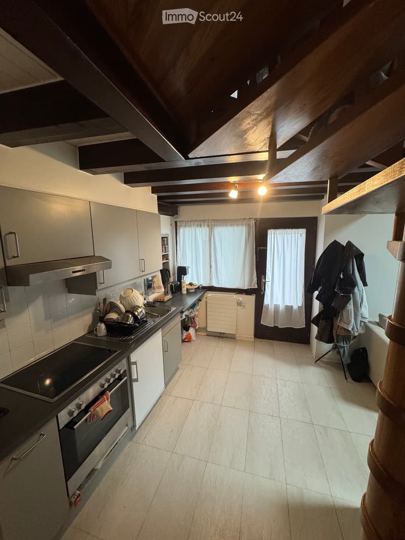 Modern kitchen with white cabinets, stainless steel appliances, and a tiled floor. Features an oven, stove, sink, and various kitchen items on the counter.
