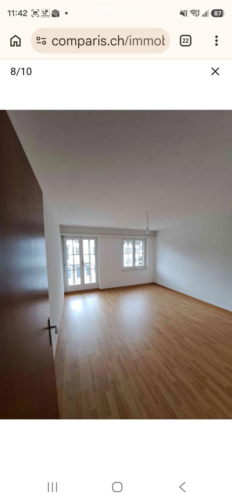 Empty room with wooden flooring, white walls, and large windows, including a glass door leading to a balcony.