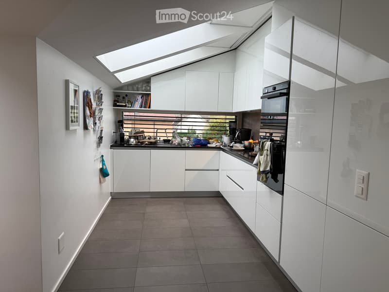 Modern kitchen with white cabinets, stainless steel appliances, and a large skylight above the island.