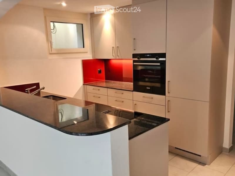 Modern kitchen with white cabinets, black countertops, and a stainless steel sink.