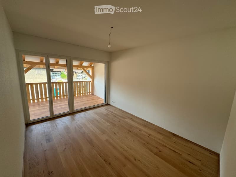 Empty room with wooden flooring and large sliding glass doors leading to a wooden deck.