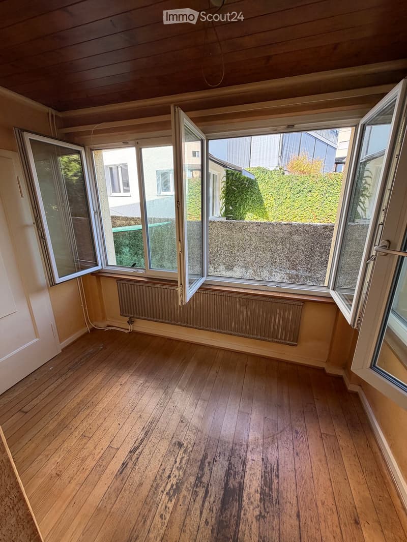 Empty room with wooden flooring, large windows, radiators, and a wooden ceiling.