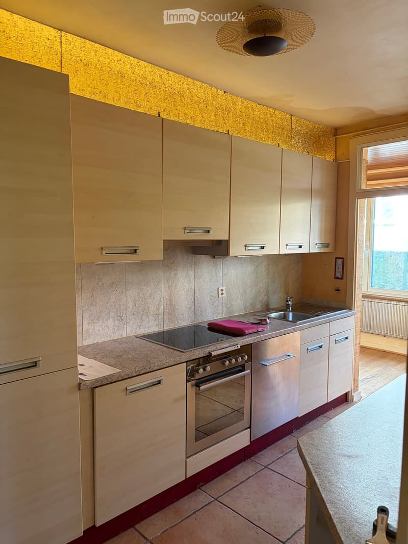 Modern kitchen with light wood cabinets, stainless steel appliances, and a granite countertop. Features an oven, sink, and faucet.
