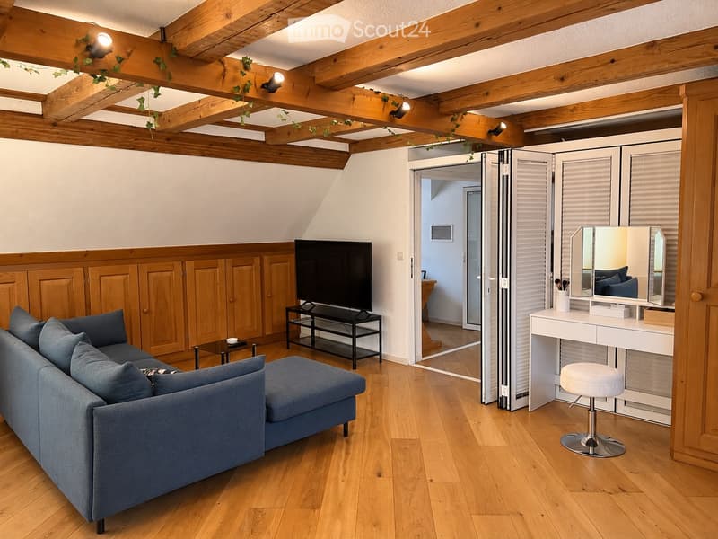 A modern living room with wooden beams, a grey sofa, coffee table, vanity with mirror, and TV stand.