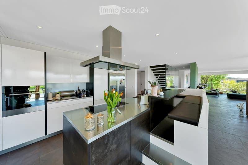 Modern kitchen with white cabinets, stainless steel appliances, island with seating, and decorative items on the counter.