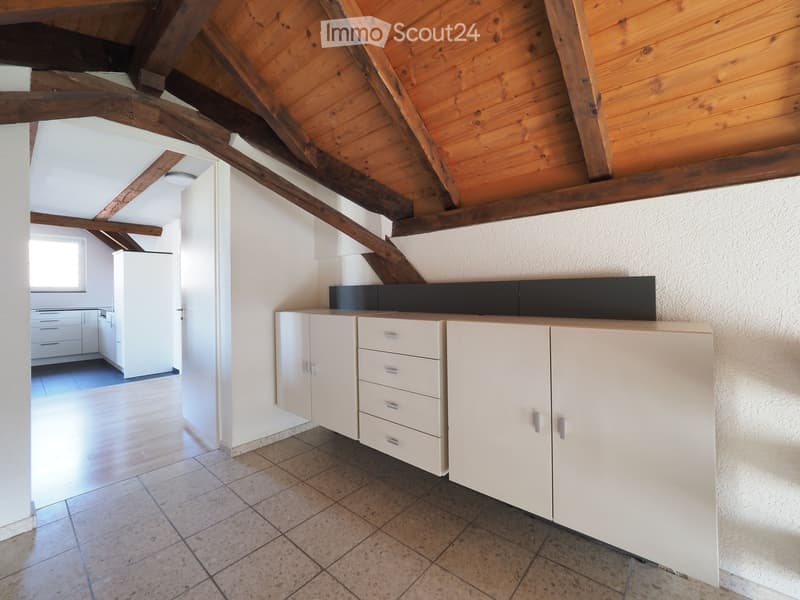 Bright kitchen with white cabinets and drawers, wooden beams on the ceiling, and a tiled floor.