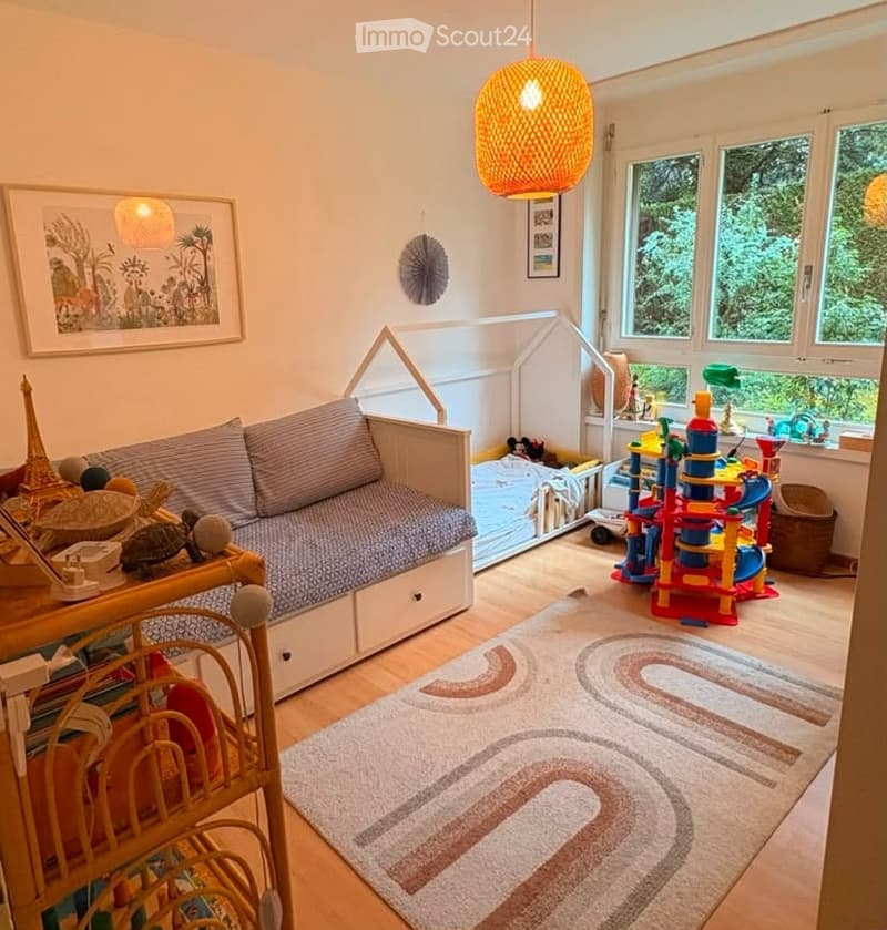 Cozy children's room with a small sofa, colorful toy tower, large rug, and decorative items.