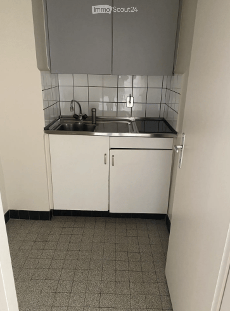 Compact kitchen with white cabinets, stainless steel sink, and tiled floor.