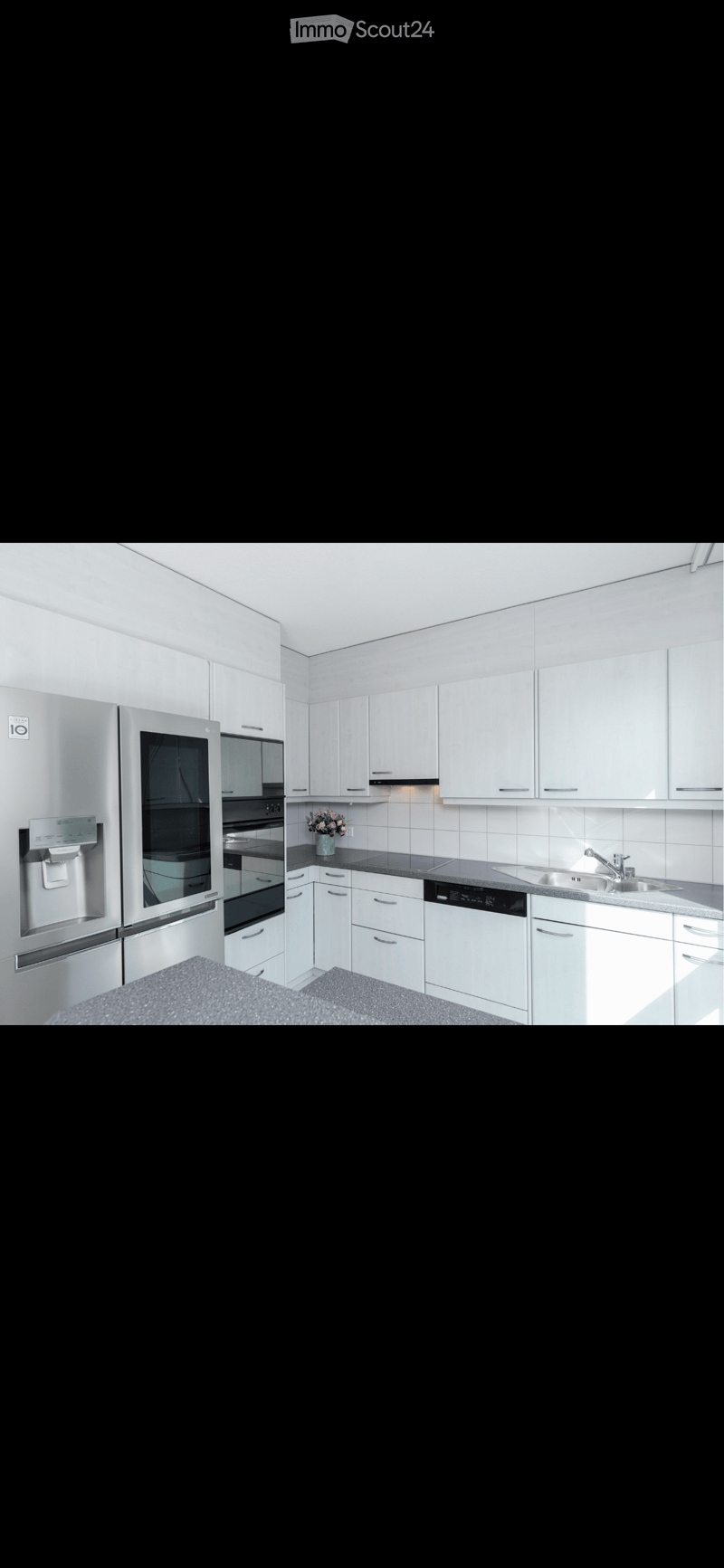 Modern kitchen with white cabinets, stainless steel appliances, and a black countertop.