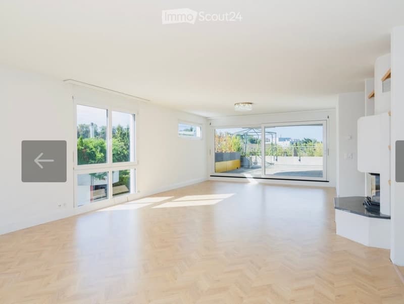 Bright, empty room with light wooden flooring, large windows, and a sliding glass door leading to a balcony or terrace area.