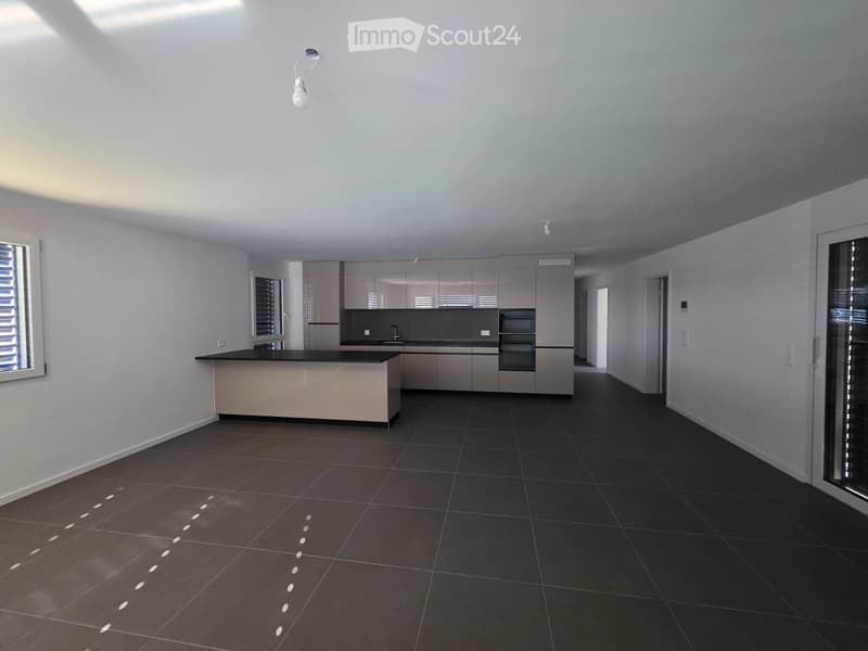 Modern kitchen with grey cabinetry, black tiled floor, and a central island.