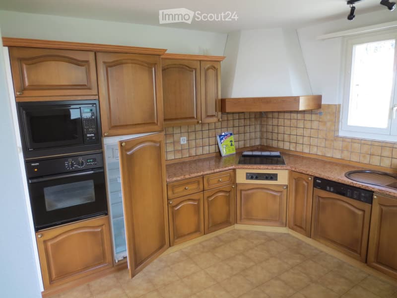 Well-lit kitchen with wooden cabinets, granite countertops, and stainless steel appliances including an oven, microwave, and dishwasher. A window provides natural light.