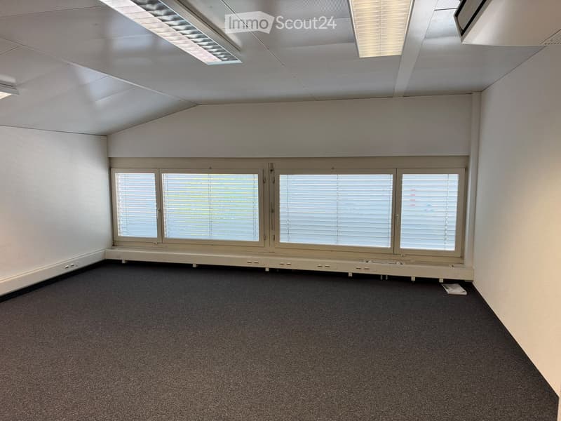 Empty room with white walls, carpeted floor, large windows with blinds, and recessed lighting.